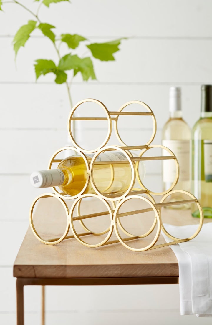 A brushed goldtone finish lends elegant shine to a graceful metal wine rack sized to hold six bottles of your favorite vintage.