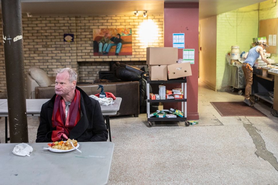 A man sits for a meal served at The Sanctuary Drop-In Centre in Toronto on March 26, 2020. People who work with the city's homeless say more are on the streets because many drop-in and respite sites, have warned of an "explosion" of COVID-19 within within Toronto's homeless population.