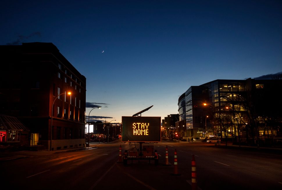 A sign telling people how to prevent COVID-19 by staying home, sits in the empty downtown, in Edmonton on March 26, 2020.