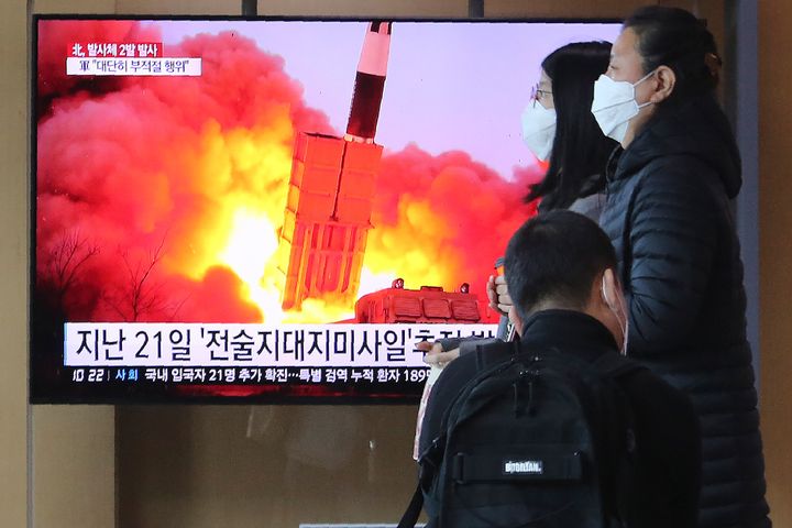 People pass by a TV screen showing a file image of North Korea's missile launch during a news program at the Seoul Railway Station in Seoul, South Korea, Sunday, March 29, 2020. 