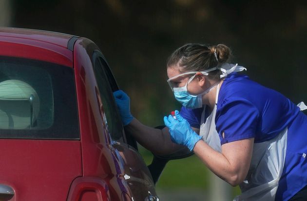 A NHS worker is tested for coronavirus at a temporary drive through testing station in the car park of Chessington World of Adventures in Chessington, England, Saturday March 28, 2020. The new coronavirus causes mild or moderate symptoms for most people, but for some, especially older adults and people with existing health problems, it can cause more severe illness or death. (Aaron Chown/PA via AP)