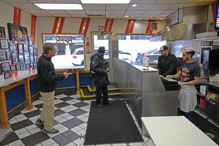 Customers, keeping their distance from one another, wait to pick up food at the famous American Coney Island diner in Detroit