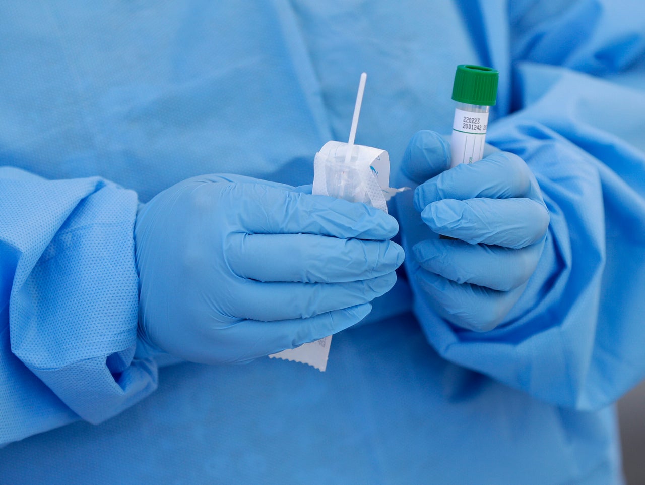 A health care worker prepares to collect a sample to test for COVID-19 at a drive-thru testing site 