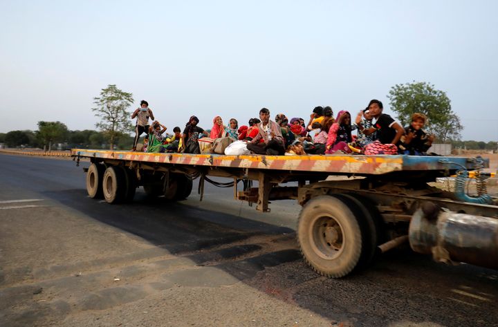 Migrant workers and their families travel in a trailer truck as they return to their villages during a 21-day nationwide lockdown, on the outskirts of Ahmedabad, March 29, 2020. 