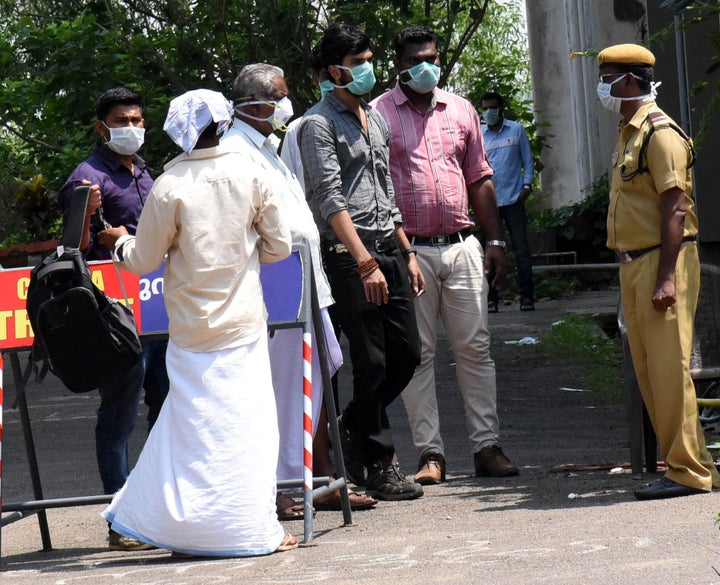 People are seen wearing masks outside the special isolation ward set up to provide treatment to novel coronavirus patients in Kerala, March 9, 2020. 