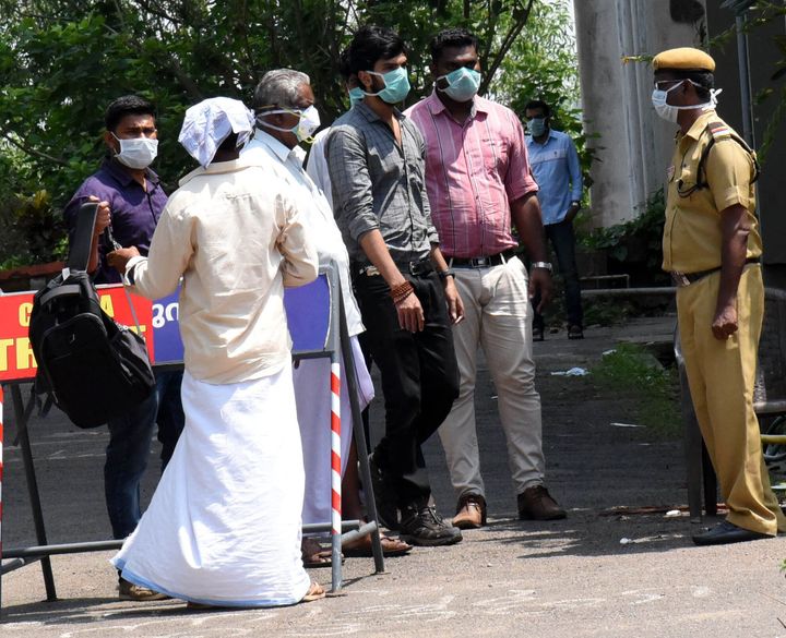 People are seen wearing masks outside the special isolation ward set up to provide treatment to novel coronavirus patients in Kerala, March 9, 2020. 