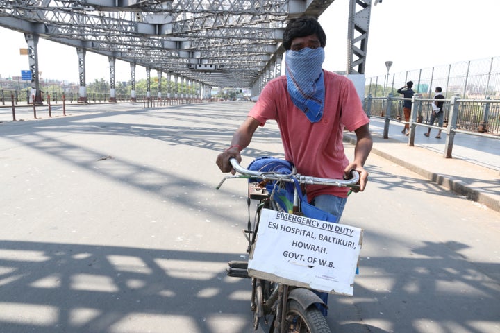 A ESI Hospital worker cycles on a deserted Howrah Bridge during the government-imposed nationwide lockdown in Kolkata on March 30,2020. 