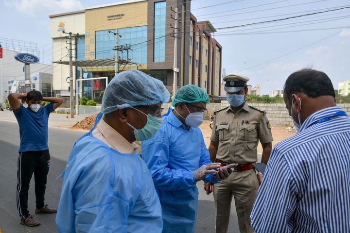 Paramedics, government municipal and police officials stand outside a private hotel in Bangalore on March 25, 2020. 