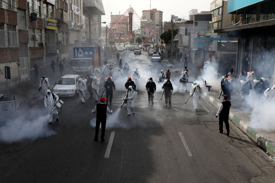 Firefighters disinfect a street against the new coronavirus, in western Tehran, Iran.