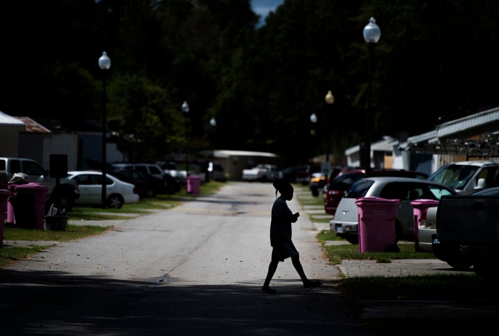 In a photo from 2018, a woman crosses the street in a mobile home park in North Carolina.