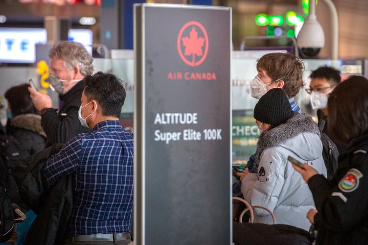 Travellers wearing face masks line up at the Air Canada check-in counters in Beijing on Jan. 30, 2020.