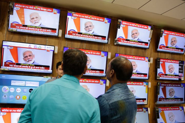 People watch Prime Minister Narendra Modi address the nation in a televised speech about COVID-19 situation, at an electronics store in Ahmedabad, March 19, 2020. 