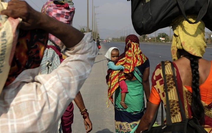 In this Sunday, March 29, 2020, photo, migrant workers walk to their villages along the Mumbai Pune highway during 2In this Saturday, March 28, 2020, file photo, a young girl lies on a luggage as she along with her family awaits transportation to her village following a lockdown 1-day countrywide lockdown in Mumbai, India. 