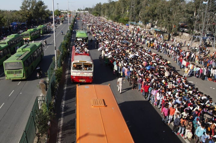 In this Saturday, March 28, 2020, photo, Indian migrant laborers wait for buses provided by the government to transport them to their hometowns, following a lockdown amid concern over spread of coronavirus in New Delhi, India. Over the past week, India’s migrant workers -- the mainstay of the country’s labor force -- spilled out of big cities that have been shuttered due to the coronavirus and returned to their villages, sparking fears that the virus could spread to the countryside.