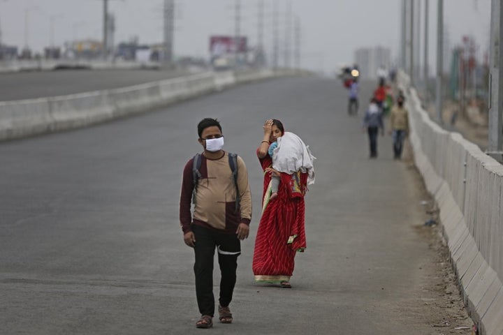 In this Thursday, March 26, 2020, photo, an Indian couple carrying an infant walk along an expressway hoping to reach their home, hundreds of miles away, as the city comes under lockdown in Ghaziabad, on the outskirts of New Delhi, India.