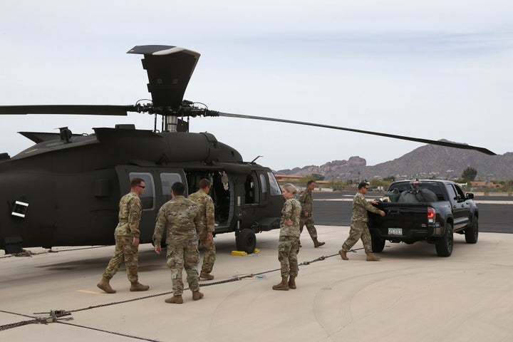 Members of an Arizona National Guard unit pause while loading a helicopter with medical supplies to be taken to the remote Navajo Nation town of Kayenta on March 31.