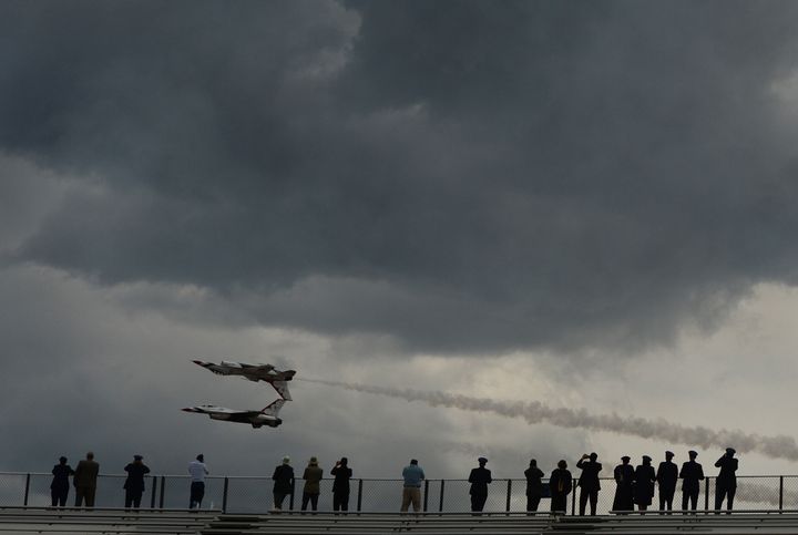 People watch an air show after graduation at the U.S. Air Force Academy in Colorado Springs. The academy said it will ease coronavirus social distancing restrictions following the deaths of two cadets.