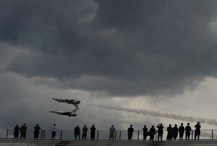 People watch an air show after graduation at the U.S. Air Force Academy in Colorado Springs. The academy said it will ease coronavirus social distancing restrictions following the deaths of two cadets.