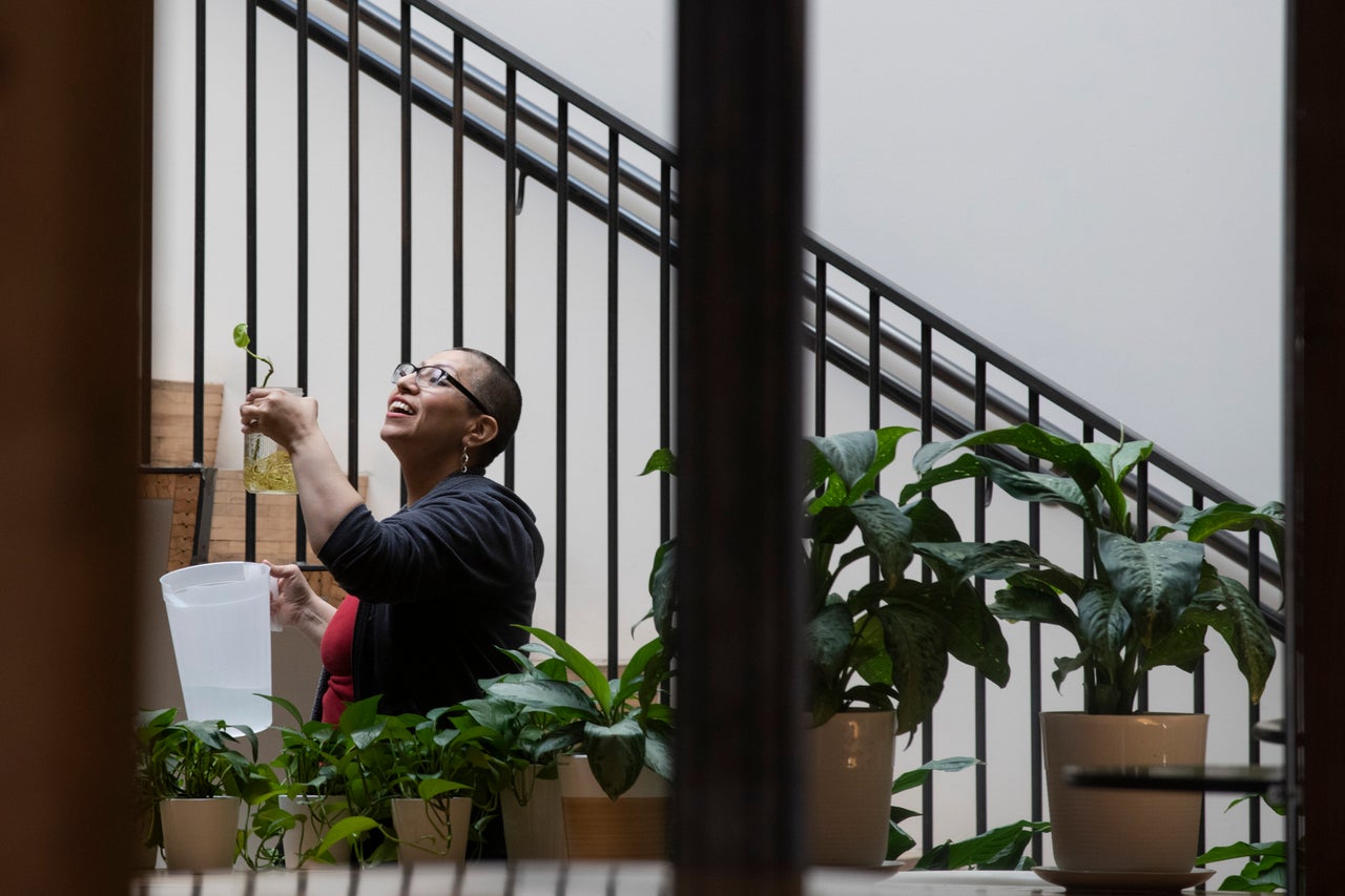 Ezzie Dominguez waters plants left behind by fellow employees at her day job as a building manager on March 31, 2020, in Denver.