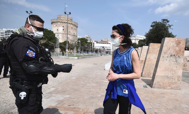 A policeman check a runner for valid documents during a lockdown order by the Greek government to control the spread of the new coronavirus in the northern city of Thessaloniki, Greece, Tuesday, March 31, 2020. Greek authorities are banning access to a popular pedestrian waterfront area in Thessaloniki, after good weather saw people congregating despite the country's lockdown measures to prevent the spread the COVID-19. (AP Photo/Giannis Papanikos)