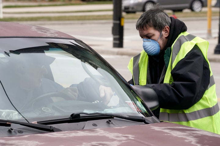 A worker helps a drive-up voter outside the Frank P. Zeidler Municipal Building on March 30 in Milwaukee. The city is now allowing drive-up early voting for the state's April 7 election.