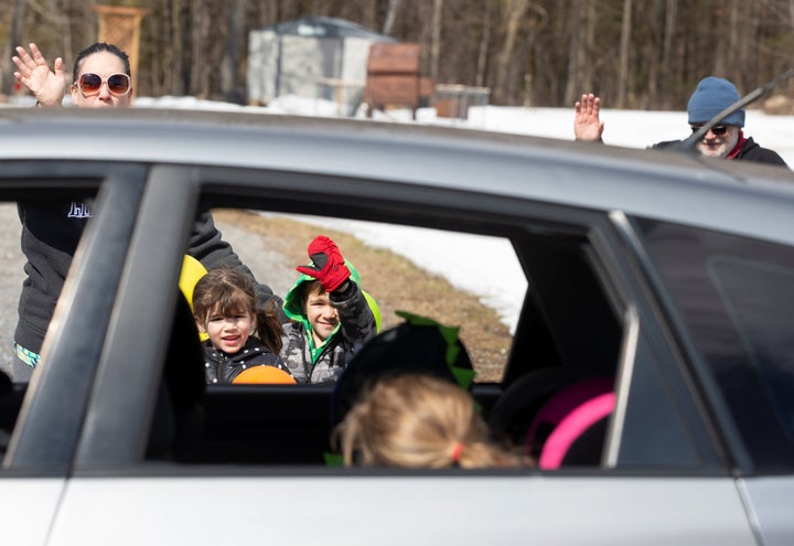 Charlotte and Calvin George wave with their parents as a car drives past their home to celebrate their fifth birthday while isolating amid the coronavirus outbreak in St-Eugene, Ont. on April 1, 2020. 