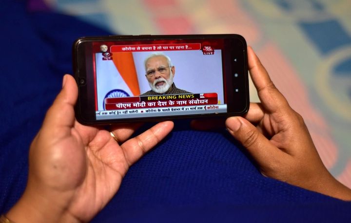 A person watches Prime Minister Narendra Modi address the nation in a televised speech about COVID-19 situation, on her mobile phone in Nagaon District of Assam.