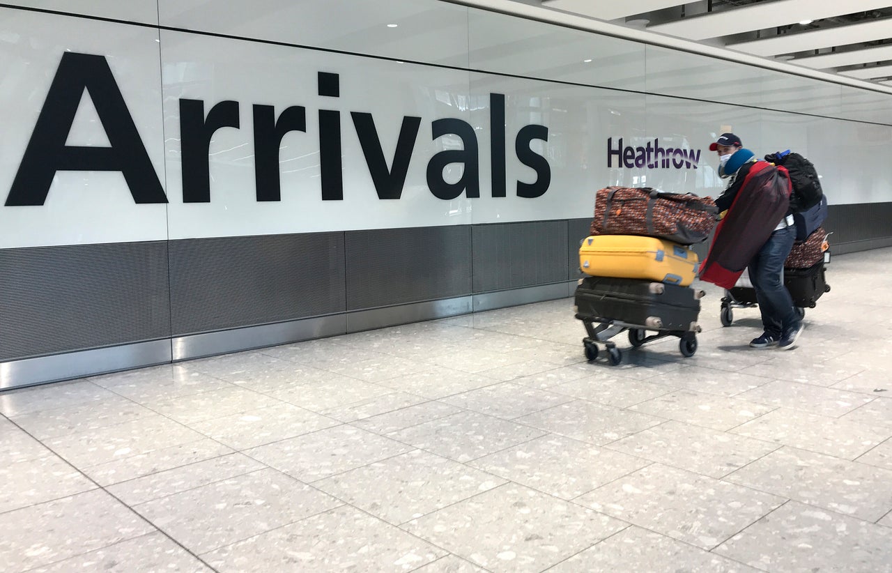 A passenger wears a mask as he arrives at Heathrow Airport Terminal 5