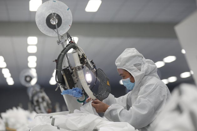 An employee works on a production line manufacturing protective suits at a medical supply factory in...