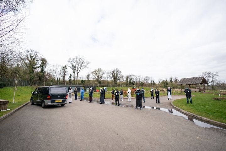 Mourners spaced out for social distance during a prayer.