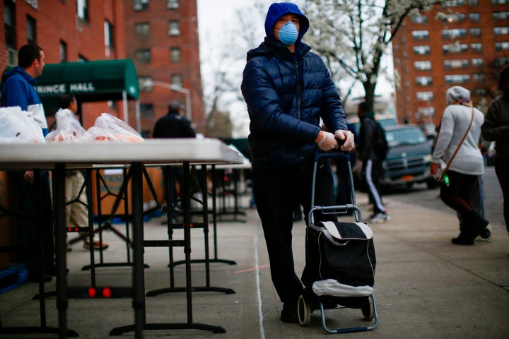 A man carries bags with food as volunteers from City Harvest distribute food in Harlem, New York City, on March 28.