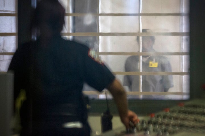 A prisoner looks at a corrections officer from behind several layers of glass and bars in the enhanced supervision housing unit at Rikers Island in New York on March 12, 2015.