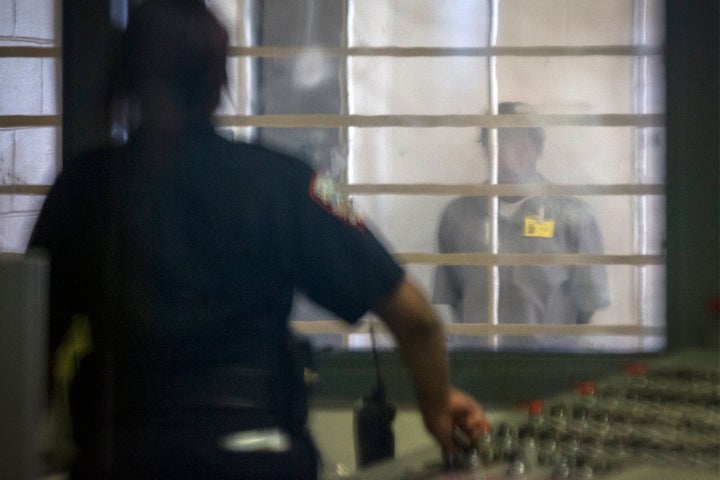 A prisoner looks at a corrections officer from behind several layers of glass and bars in the enhanced supervision housing un