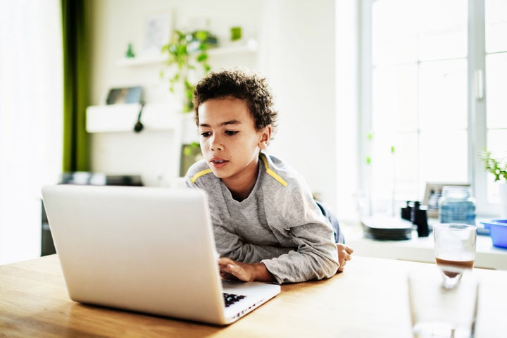 A young boy at home over the weekend using a laptop to do his homework.