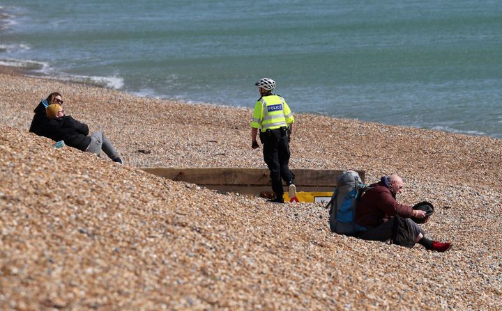 A police officer asks people to leave the beach in Brighton, south England, as the UK continues to implement a social lockdown.