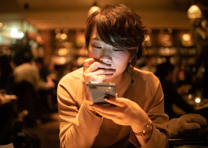 Young woman using smart phone in cafe after work