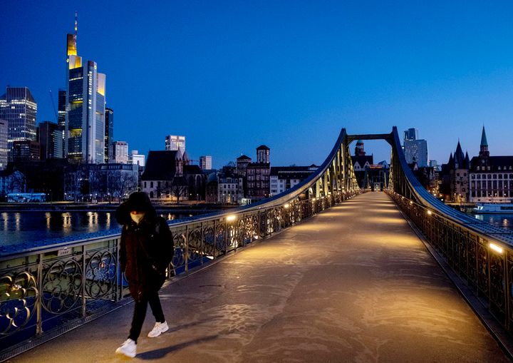 Ο μοναχικός δρόμος της Γερμανίας.Μια γυναίκα περνά μια γέφυρα και πίσω της οι τράπεζες της Φρανγκφούρτης συμπεριλαμβανομένης και της ΕΚΤ.(AP Photo/Michael Probst)