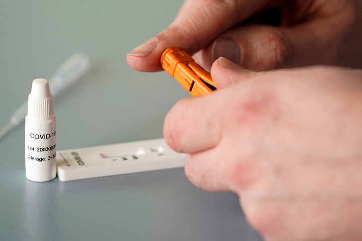 A worker demonstrates the use of a Coronavirus 10 minute blood test on March 16. (Photo illustration, by Christopher Furlong/Getty Images)