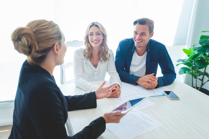 A mortgage broker sits with a young couple to go over finances in this stock image. A CMHC survey suggests nearly half of Canadians used brokers to get a mortgage in 2019.