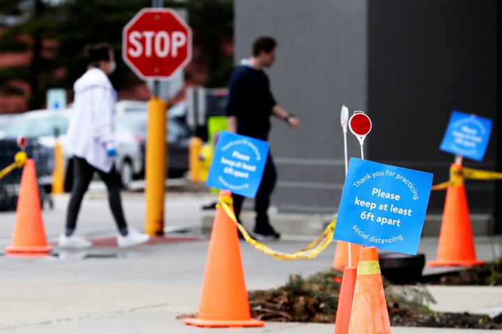 Signs on social distancing practices are posted outside a Walmart store in Vernon Hills, Illinois. In addition to limiting the number of customers inside stores at any time, the company has created one-way aisles inside to make it easier for people to keep their distance.