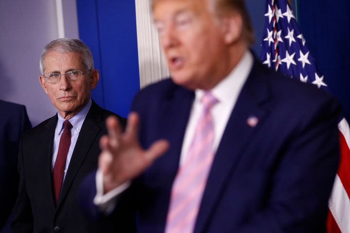 Dr. Anthony Fauci, director of the National Institute of Allergy and Infectious Diseases, left, listens as President Donald Trump speaks during a coronavirus task force briefing at the White House, April 4, in Washington.