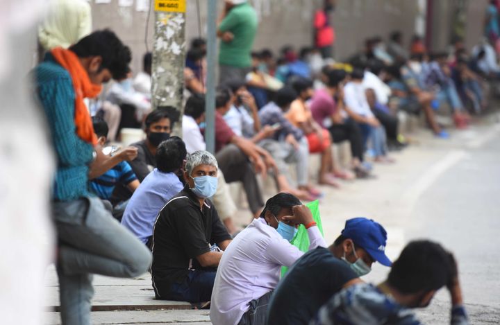 People wait to collect food at a food distribution on day thirteen of the 21-day nationwide lockdown, at New Ashok Nagar on April 6, 2020 in New Delhi.