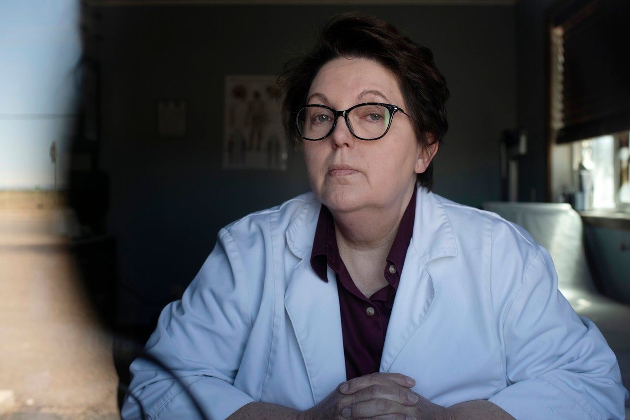 Tracy Scott poses through a window in her Bennett, Colorado, clinic. Connectivity issues make it hard for her patients to use telemedicine services, which allow her to hold remote appointments during social distancing.