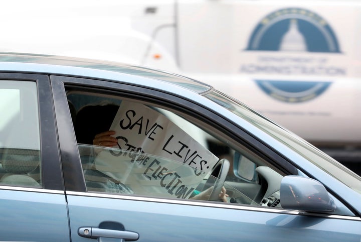 An opponent of a Wisconsin Supreme Court decision to proceed with the state's spring election amid coronavirus concerns displays a sign in her car in Madison, Wisconsin, Tuesday, April 7. (John Hart/Wisconsin State Journal via AP)