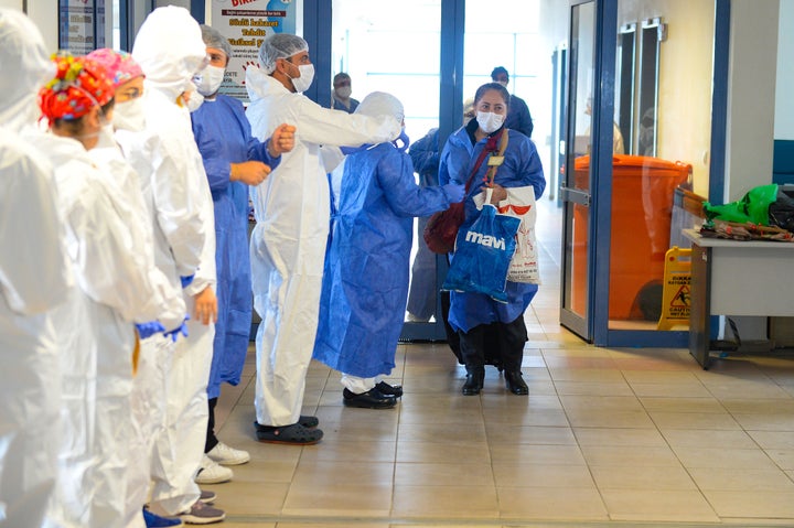 In Igdir, Turkey, doctors and nurses gather Tuesday to applaud as a COVID-19 patient is discharged from the hospital. Research has been unclear on how long a patient might remain infectious after symptoms have ended.