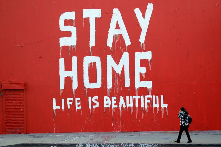 A pedestrian walks past a stay-at-home mural April 2 in Los Angeles, where schools and nonessential businesses are closed and the California governor has ordered people to stay home. 