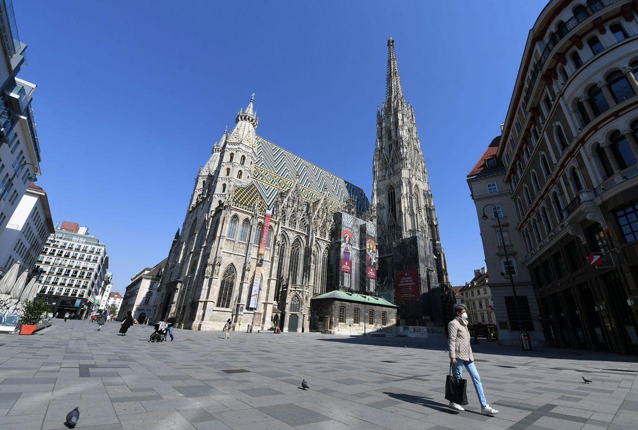A woman with face protection mask walks past Saint Stephen's Cathedral (Stephansdom) in Vienna.