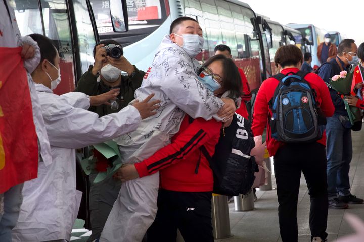 A medical worker from China's Jilin Province, in red, embraces a colleague from Wuhan as she prepares to return home at Wuhan Tianhe International Airport in Wuhan in central China's Hubei Province, on April 8, 2020.