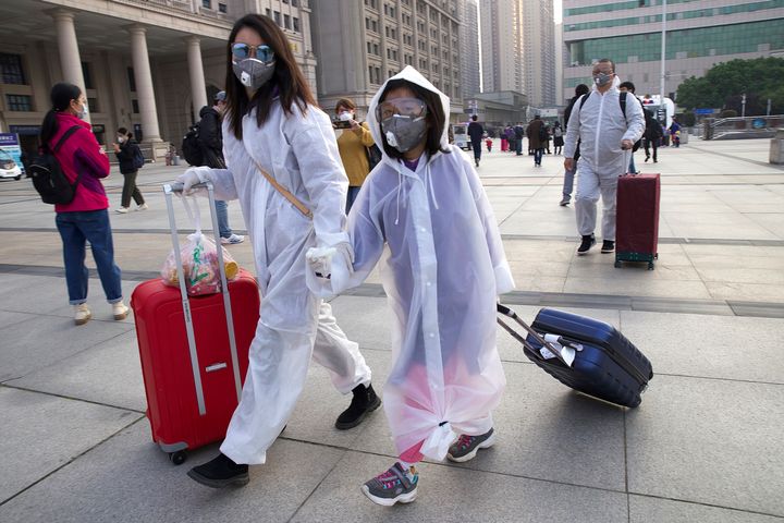 Passengers wearing face masks and raincoats to protect against the spread of new coronavirus walk outside of Hankou train station after of the resumption of train services in Wuhan on Wednesday.