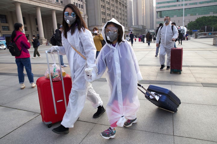 Passengers wearing face masks and raincoats to protect against the spread of new coronavirus walk outside of Hankou train station after of the resumption of train services in Wuhan on Wednesday.